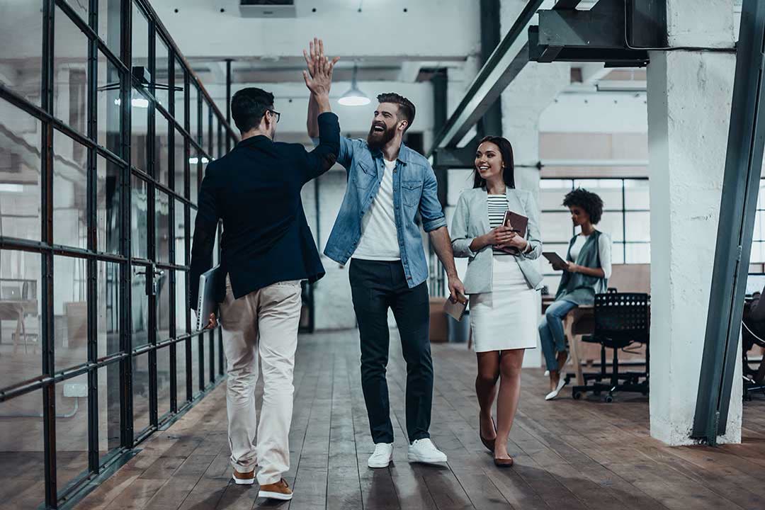 Team geht gut gelaunt durch ein Büro